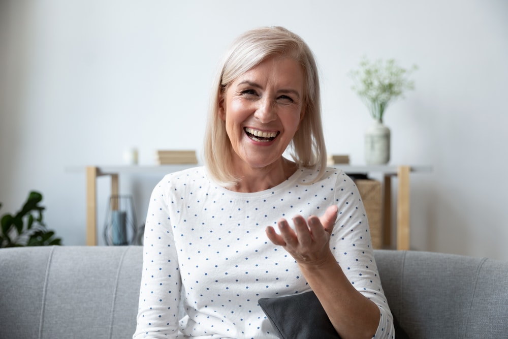 Older woman smiling while seated on a sofa