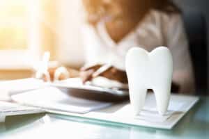 Dental model beside treatment paperwork and a calculator