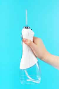 Hand holding a water flosser for mini implant denture care