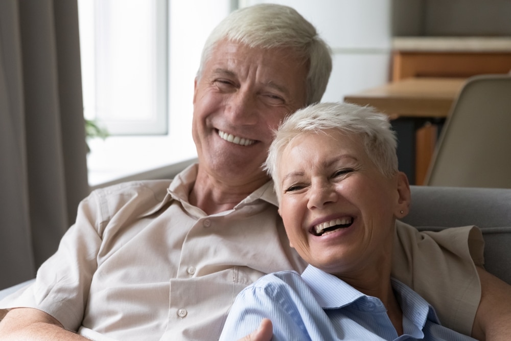 Older couple smiling together with healthy-looking teeth