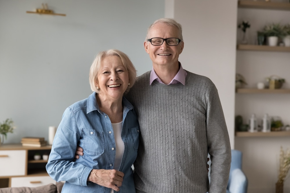 Smiling senior husband and wife embracing at home